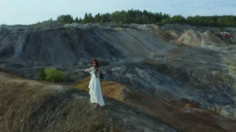 Drone camera flies over the quarry mountain where a violinist in white long dres Video stock 229409283