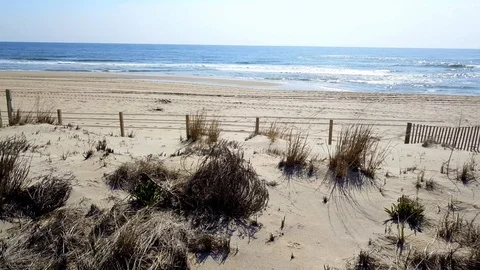 Drone camera flies sideways along beach sand dune in Ocean City, Maryland Stock Footage 89451920