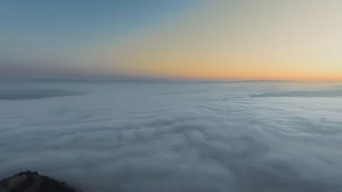 Drone camera flies through clouds over mountain peaks and morning sunrise Video stock 126678323