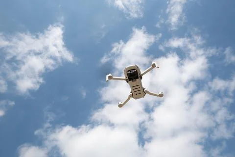 Drone with camera flying over the blue cloudy sky. Aerial landscape photography. Stock Photos