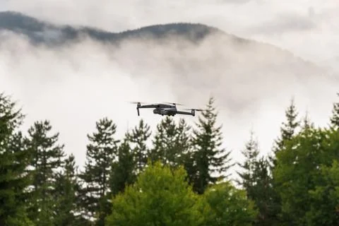 Drone with camera flying over mountain fields. Stock Photos