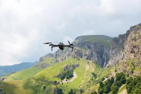 Drone with camera flying over mountain fields. Stock Photos