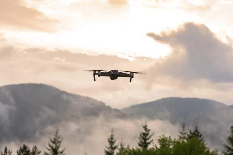 Drone with camera flying over mountain fields. Stock Photos