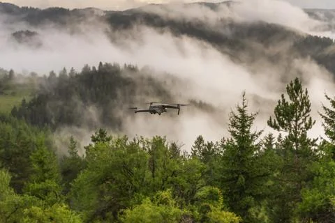 Drone with camera flying over mountain fields. Stock Photos