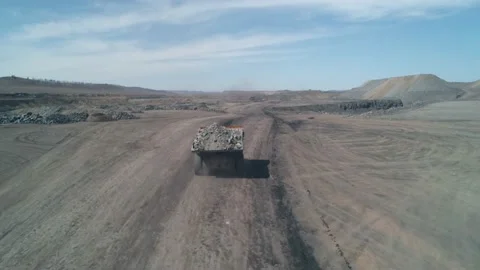 Drone camera follows a dump truck loaded with quarry coal. Truck is symbol of Stock Footage 203918368