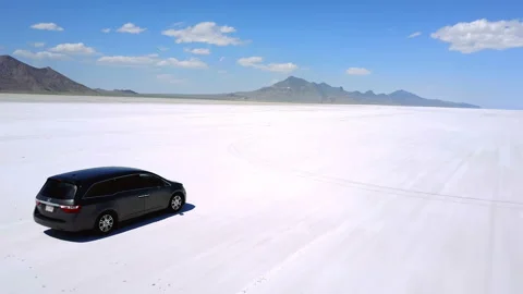 Drone camera follows silver minivan car driving towards far mountains on Stock Footage 120482790