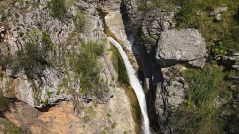 Drone with camera goes down along the cliff, where a stream of water noisily Stock Footage 160148846