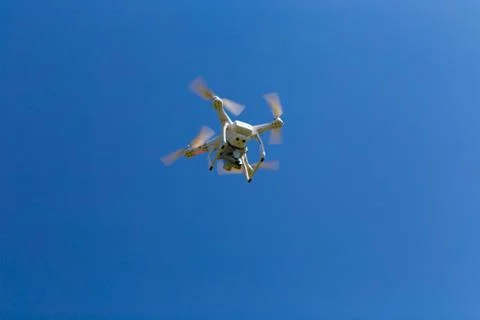 Drone with camera hovering in blue sky. Stock Photos