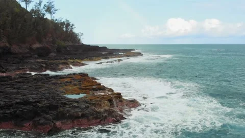 Drone camera moves over the foaming waves hitting rocky shore on a clear day Stock-Footage 136418953