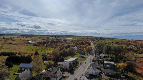 Drone camera moves over a road with cars near a village with green fields Video stock 120654283
