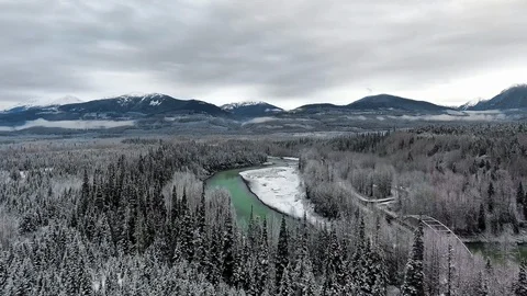 Drone camera moves over the snowy forest the pond near the mountains Video stock 119234836