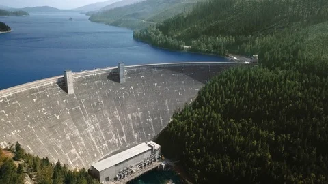 Drone camera moving reservoir in front of a dam at the foot of wooded mountains Stock-Footage 123392739