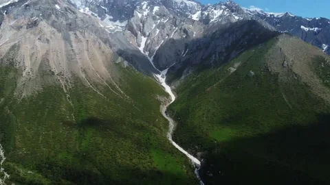 Drone camera pans up from top down view to reveal majestic mountain peaks Stock-Footage 337141223
