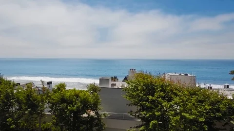 Drone camera rises above a house on a sandy beach by the ocean (Malibu Video stock 126675822