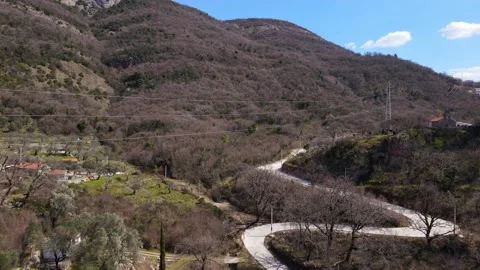 Drone with camera rises over hills covered with forest, and road running through Stock Footage 162004314