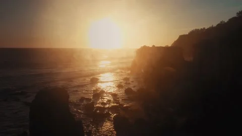 Drone camera rising over rocks of El Matador Beach to the bright setting sun Video stock 137405788