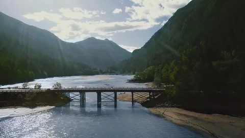 Drone camera shoots a bridge over a river between mountains with a dense forest Video stock 123392591