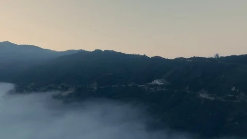 Drone camera shoots mountains with a dense forest and a winding road in fog from Stock Footage 126678102
