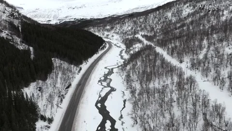Drone captured aerial view showcasing a winter scene in Norway with a curving Stock Footage 330376553
