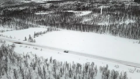 Drone captured footage shows a van traveling along an asphalt road through a Stock Footage 330376556