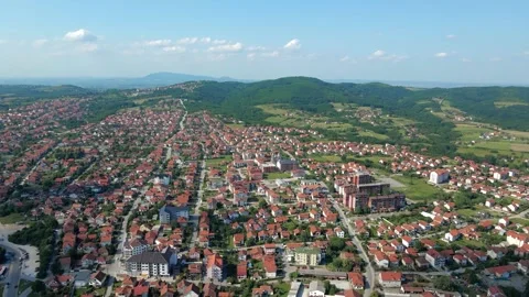 Drone captures beautiful townscape with mountains in background under blue sky Stock Footage 258602999