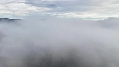 Drone captures cloudy forest landscape, overcast conditions obscure forest Stock Photos
