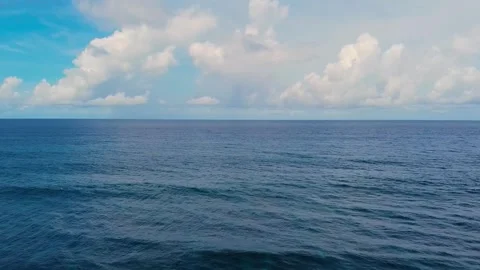 Drone captures the deep blue sea beneath a partly cloudy sky revealing natural c Stock Footage 309266173