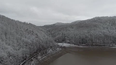Drone captures the drained lake and dam surrounded by snowy terrain, with e.. Stock Footage 297178185