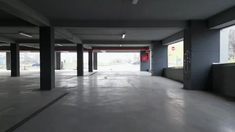 A drone captures an empty underground parking garage with concrete pillars and Stock Footage 304444356