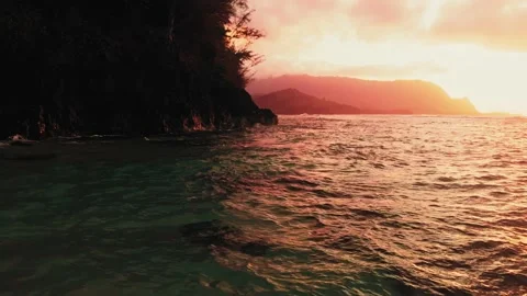 Drone captures golden sunset over the ocean and black cliff in the shadows Video stock 136428355
