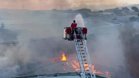 Drone captures intense moment of a firefighter on a ladder dousing a Stock Footage 282505838
