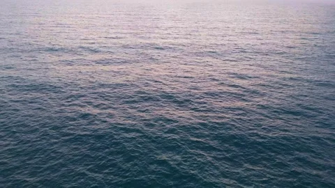 Drone captures the ocean at sunrise, slow-motion waves in blue and orange. .. Video stock 285597895