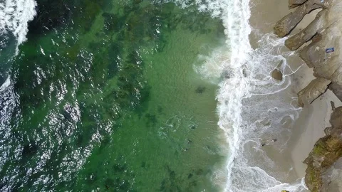 Drone captures ocean waves crashing on rocks on a sunny San Diego summer day Stock Footage 97973329
