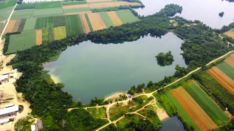 Drone captures a patchwork of agricultural fields with a large lakes and trees Stock Footage 269165027