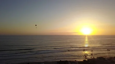 Drone captures powered paraglider over beach as it turns by afternoon sun Stock Footage 98267698