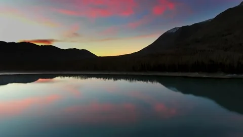 Drone captures the reflection of magenta clouds in a lake near a mountain Video stock 131258659
