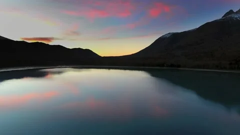 Drone captures the reflection of magenta sunset in a lake with forest Video stock 131258520