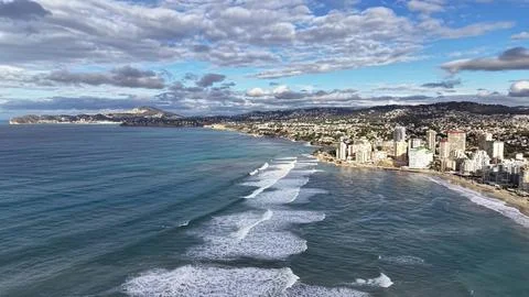 Drone captures rhythmic wave patterns along coast with highrise buildings l.. Stock Photos