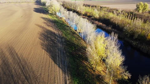 Drone captures a river surrounded with empty agricultural fields and trees Stock Footage 263187996