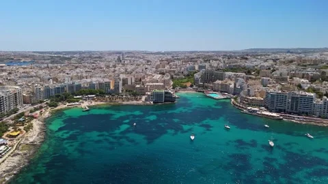 A drone captures Sliema's waterfront with turquoise water and harbor boats Stock Footage 336469525