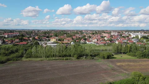 Drone captures a townscape surrounded with cultivated land under bright blue sky Stock Footage 262835711