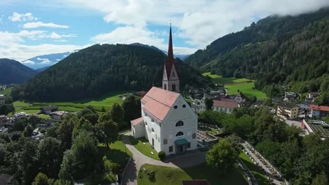 Drone captures valley town scene, Wide shot showcasing church over lush Stock Footage 323980726