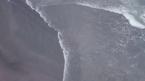 The drone captures the waves of the sea that beat against the dark shore. Stock Footage 155973067