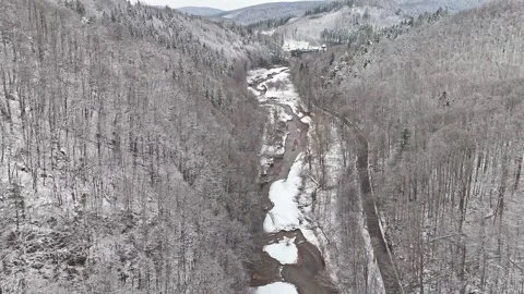 Drone captures a winding stream in a dried lakebed covered in snow. The dar.. Stock Footage 295764179