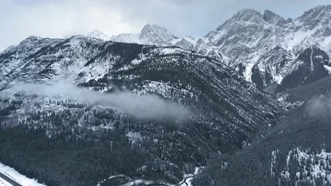 Drone capturing high mountains in snow, black forest small cloud in Alberta Video stock 143234520