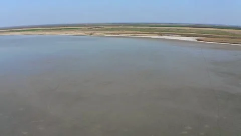 Drone capturing large lake and land on shore under blue sky in nature reserve Stock Footage 270501954
