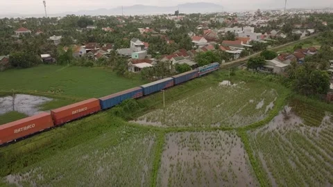 A drone chases a freight train as it passes a Vietnamese village. Video stock 255688274