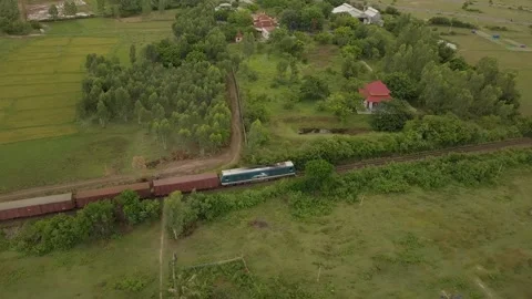 A drone chases a freight train as it passes a Vietnamese village. Stock Footage 255688549