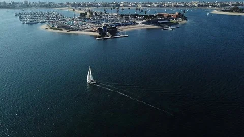 Drone chases small white sailboat towards harbor on Mission Bay Stock Footage 86129043