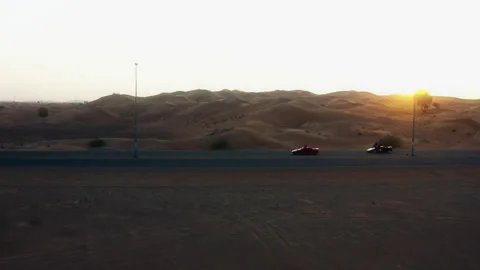 Drone chasing accelerating convertible through Dubai desert at sunset Stockbeeldmateriaal 345097491